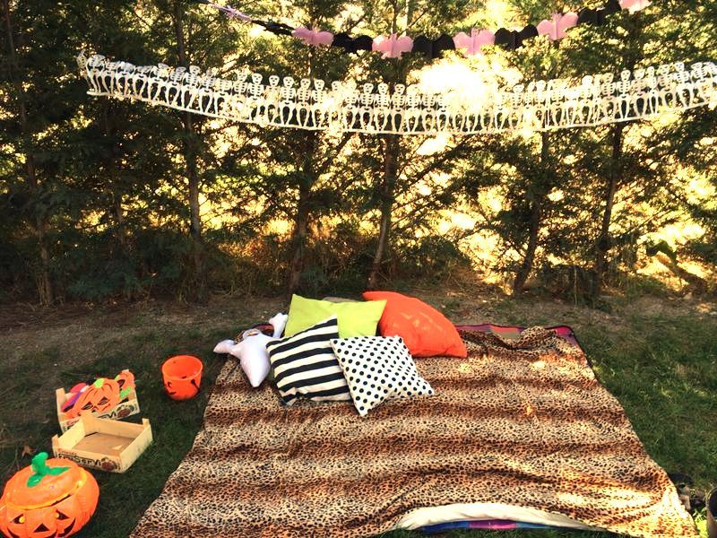  picnic de halloween con manta de leopardo y cojines verde y naranja y caretas de foami